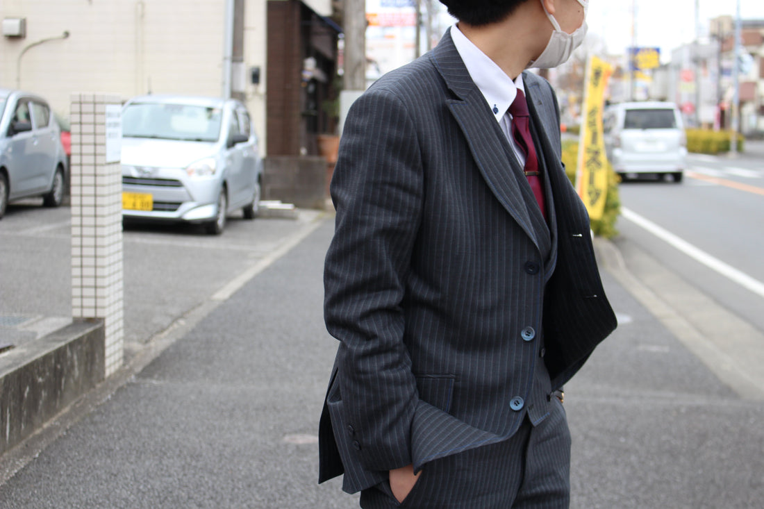 グレーのメンズスーツを着ている人が後ろを振り返っている写真。