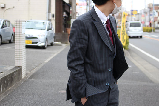 グレーのメンズスーツを着ている人が後ろを振り返っている写真。